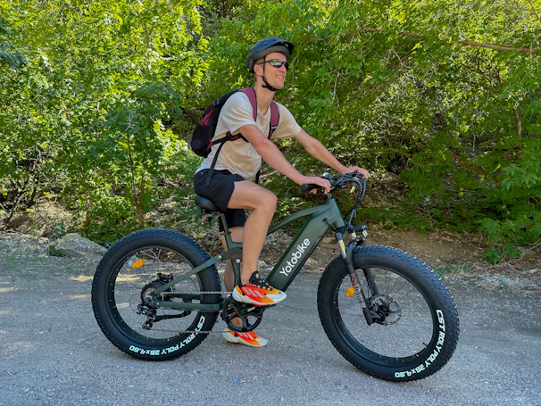 A happy rider wearing a helmet, enjoying a ride on a quiet park trail with an electric bike.