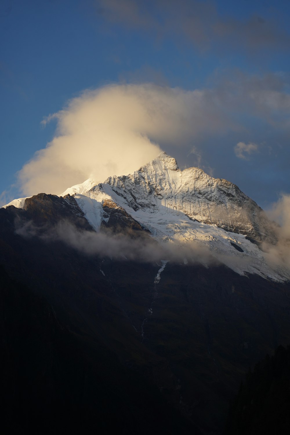 a snow covered mountain under a cloudy blue sky