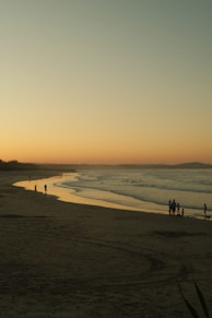 a group of people standing on top of a sandy beach