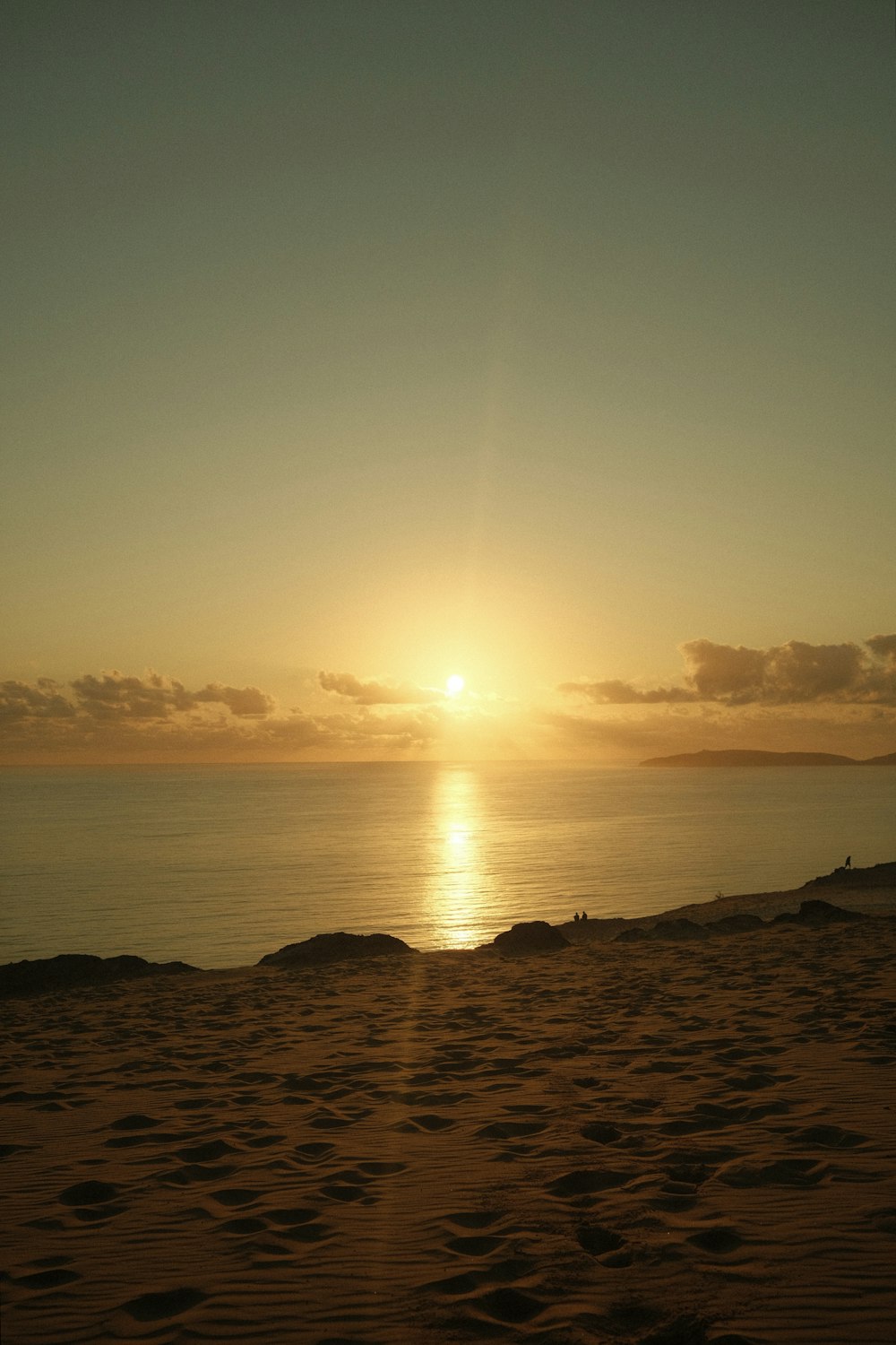 the sun is setting over the ocean on the beach