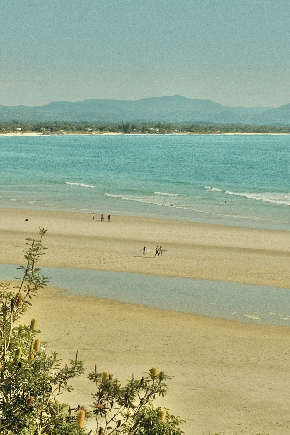 a group of people walking along a beach next to the ocean