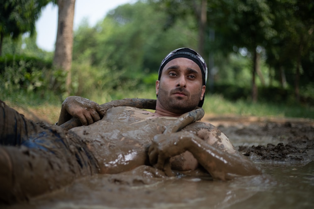a man laying in the mud in a river