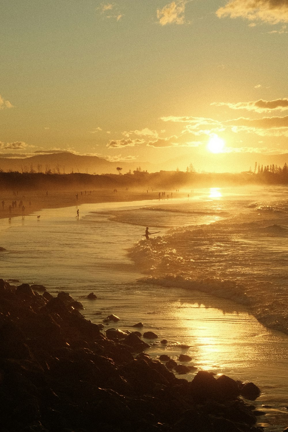 a group of people walking along a beach at sunset