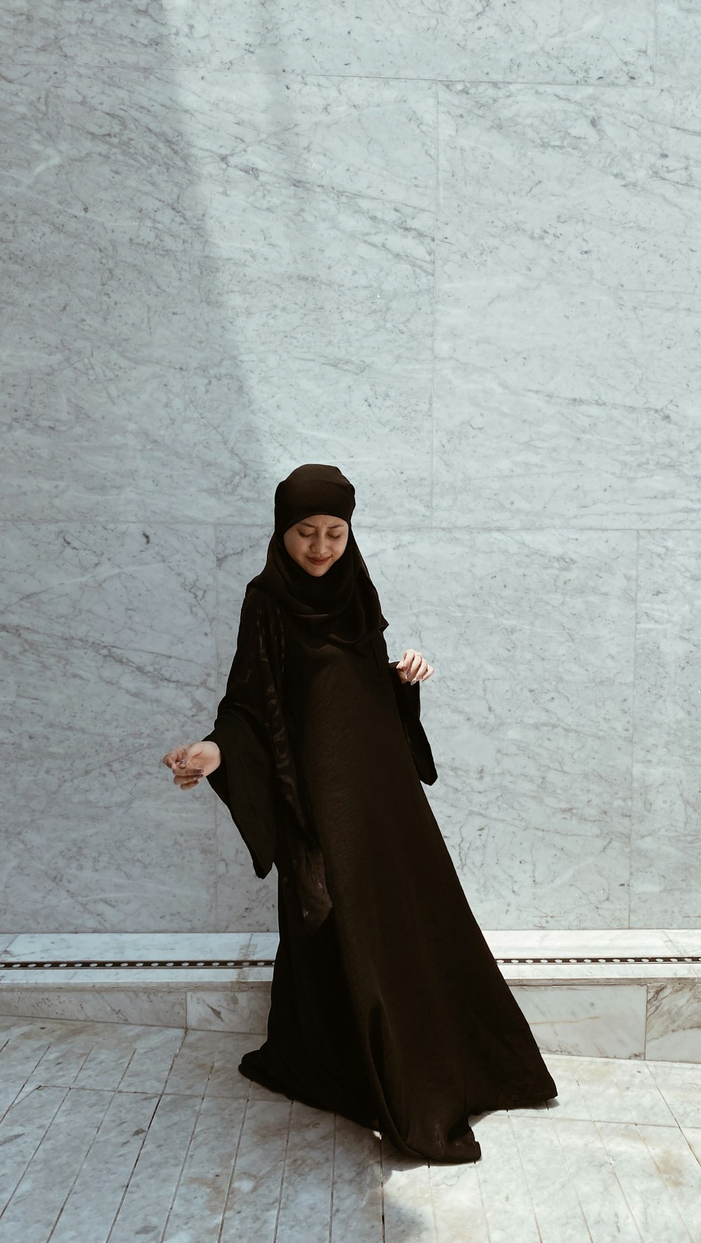 a woman in a black hijab standing in front of a wall