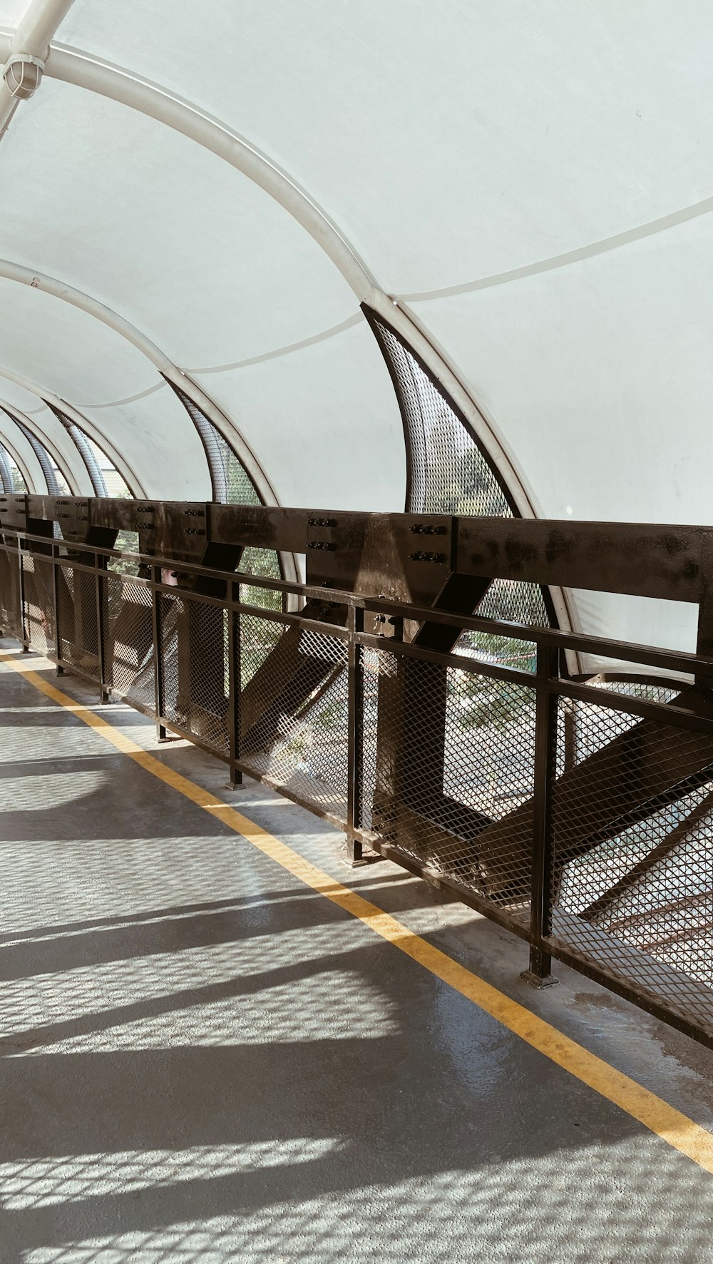 a walkway with metal railings and a yellow line