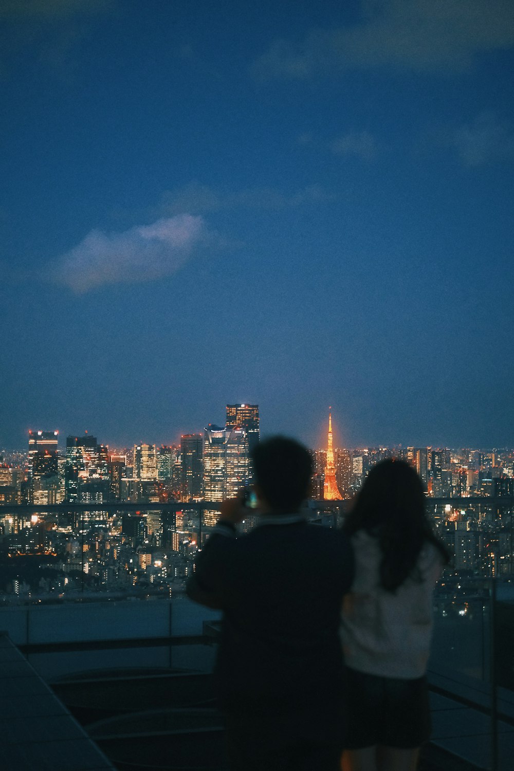 un hombre y una mujer parados frente a una ciudad por la noche