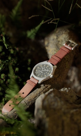 Minimalist watch on a wrist against a backdrop of natural stone and greenery
