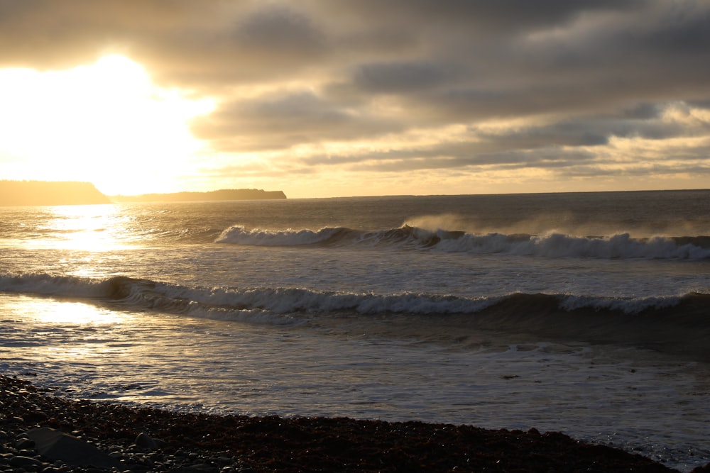 the sun is setting over the ocean with waves