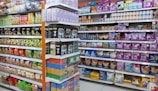 Shelves filled with a variety of packaged products, including snacks and pet food. The left side features chips and snacks in colorful bags, while the right side displays pet food bags and cans. The items are neatly organized, offering a vibrant and busy visual.
