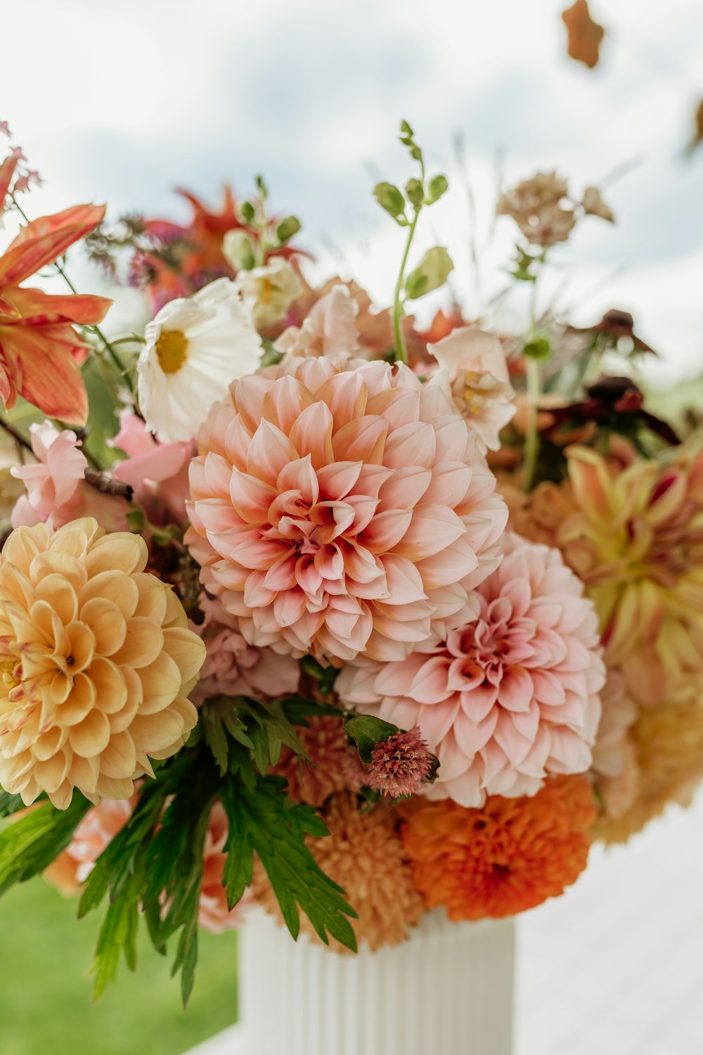 a white vase filled with lots of different colored flowers