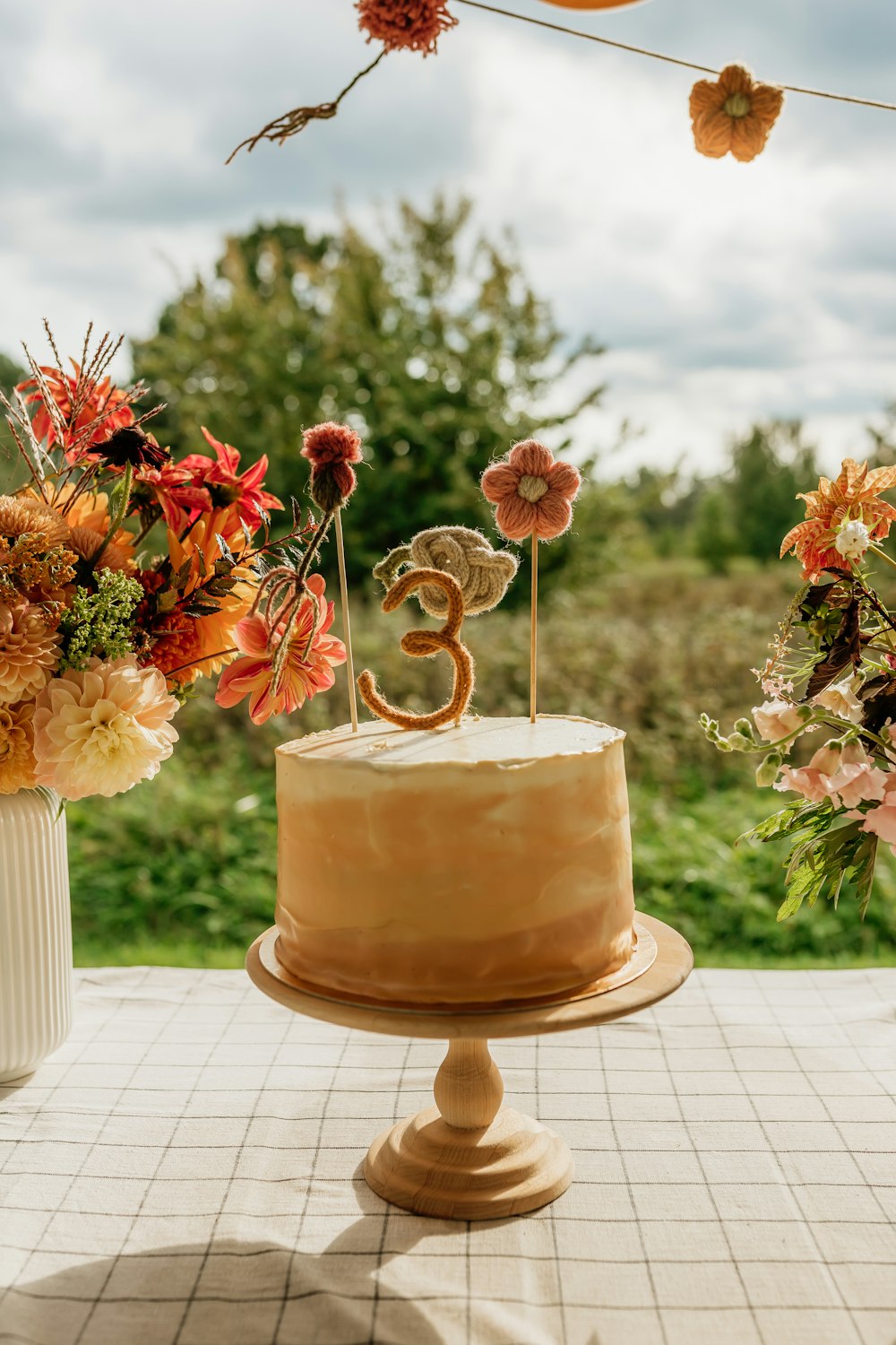 un pastel encima de una mesa junto a un jarrón lleno de flores