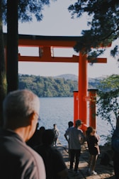 Visitors enjoying a vibrant festival at a red torii gate under a blue sky.