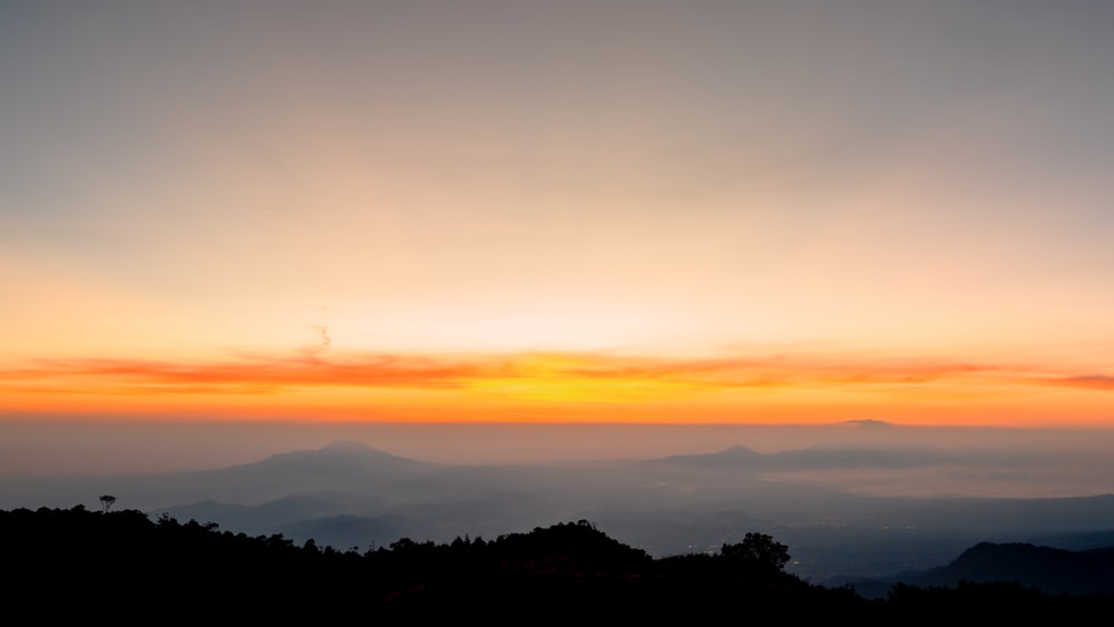 the sun is setting over a mountain range