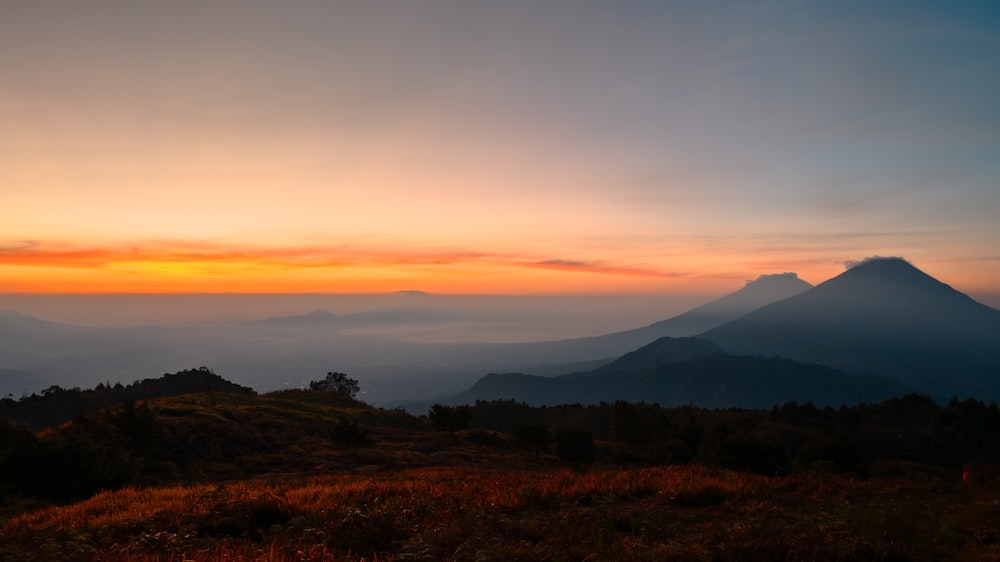 the sun is setting over a mountain range