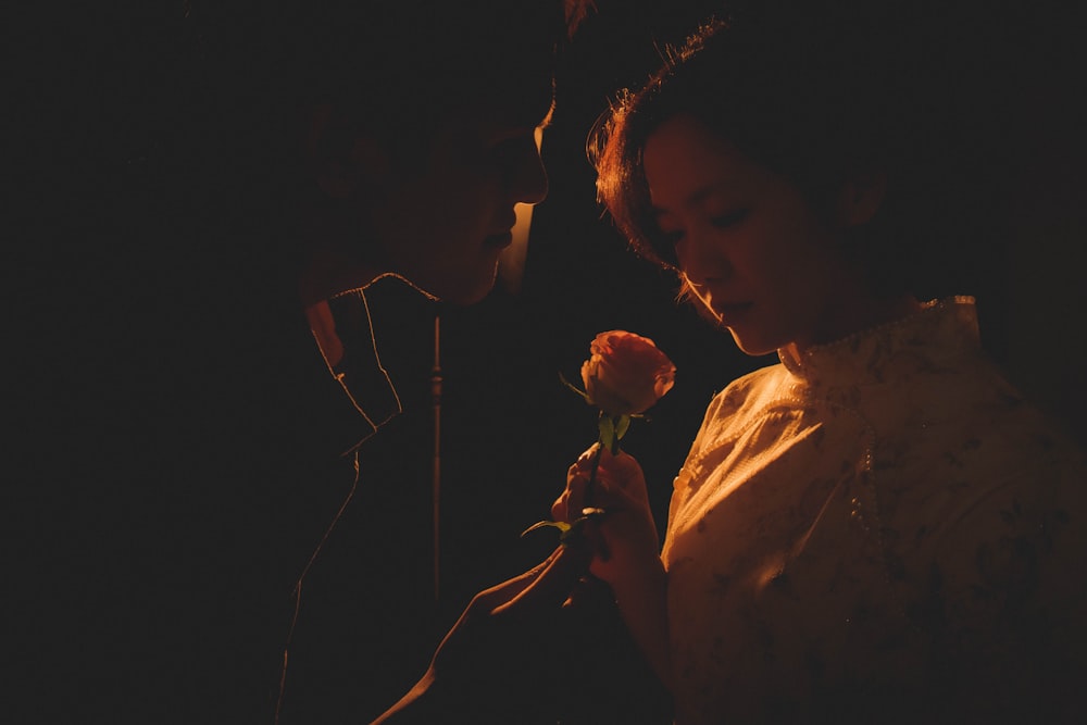 a woman holding a flower next to a man