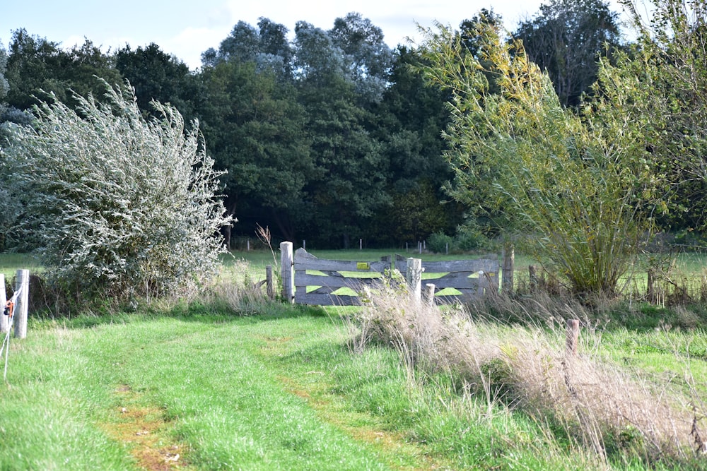 a wooden fence in a grassy field next to trees