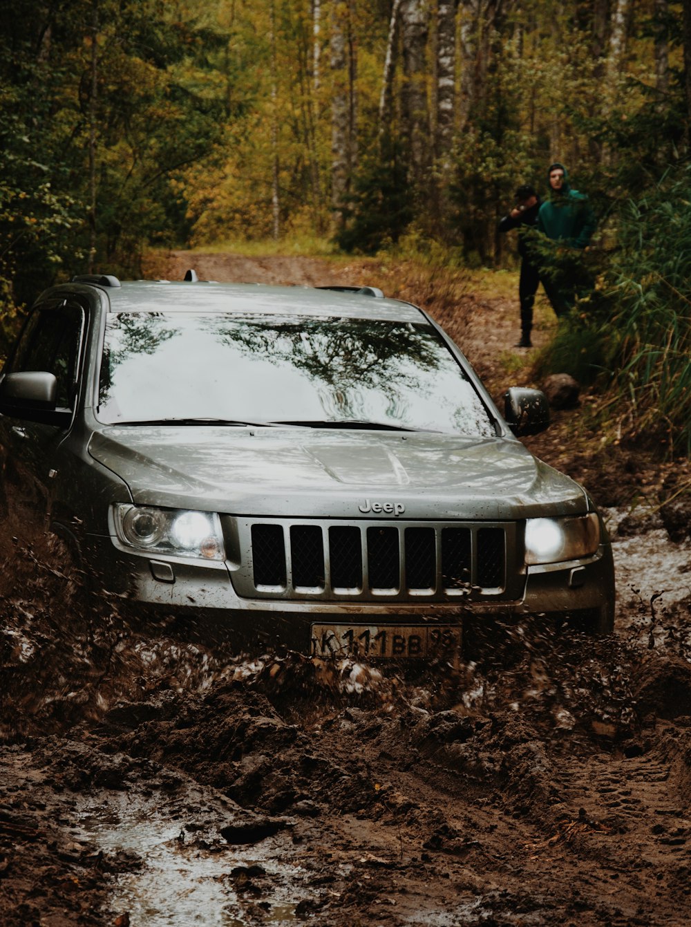 a jeep driving through a muddy road in the woods