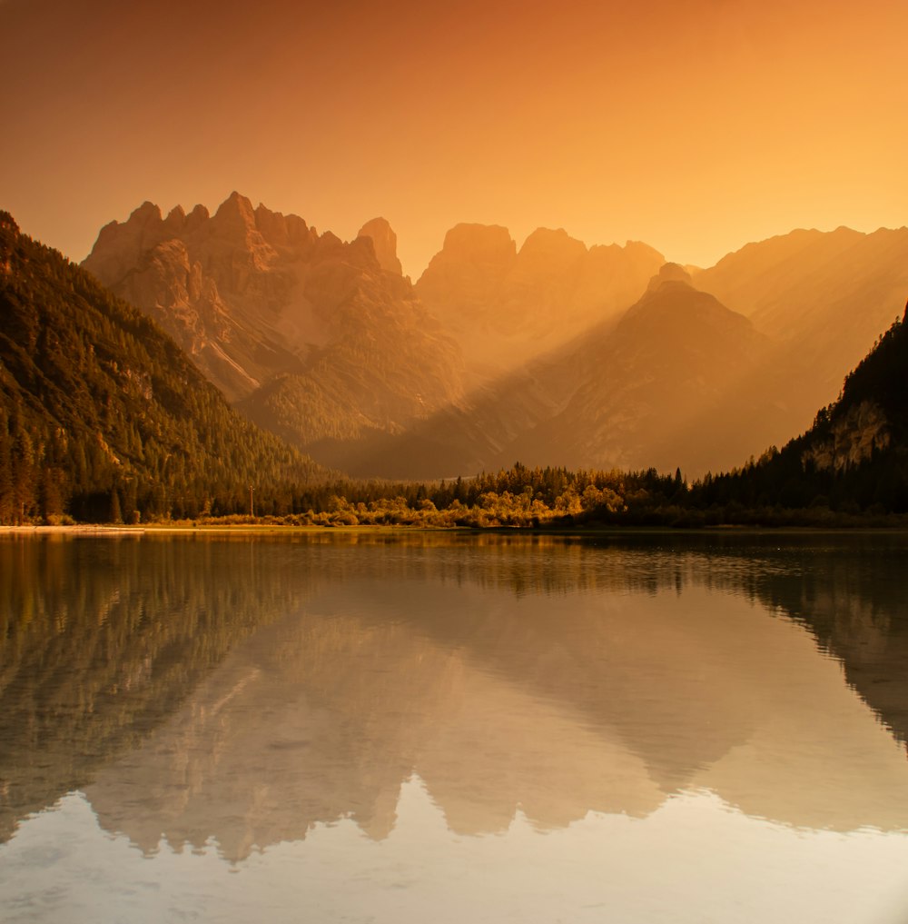 a lake with mountains in the background at sunset