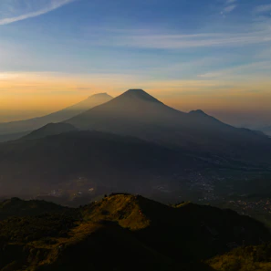 A panoramic view of layered mountain ranges fading into the distance at sunset