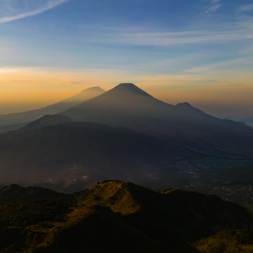 A panoramic view of smoky mountain ridges fading into the mist at sunset.
