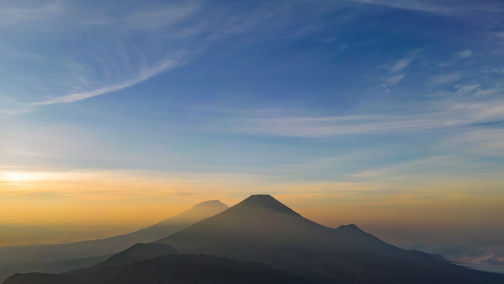 uma vista de uma montanha ao pôr do sol do topo de uma colina