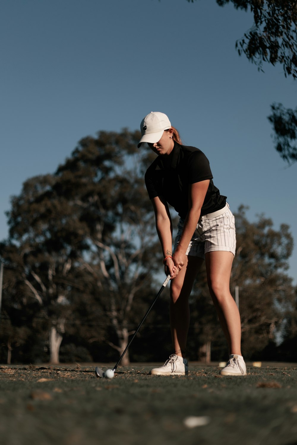 a woman in a black shirt and white shorts playing golf