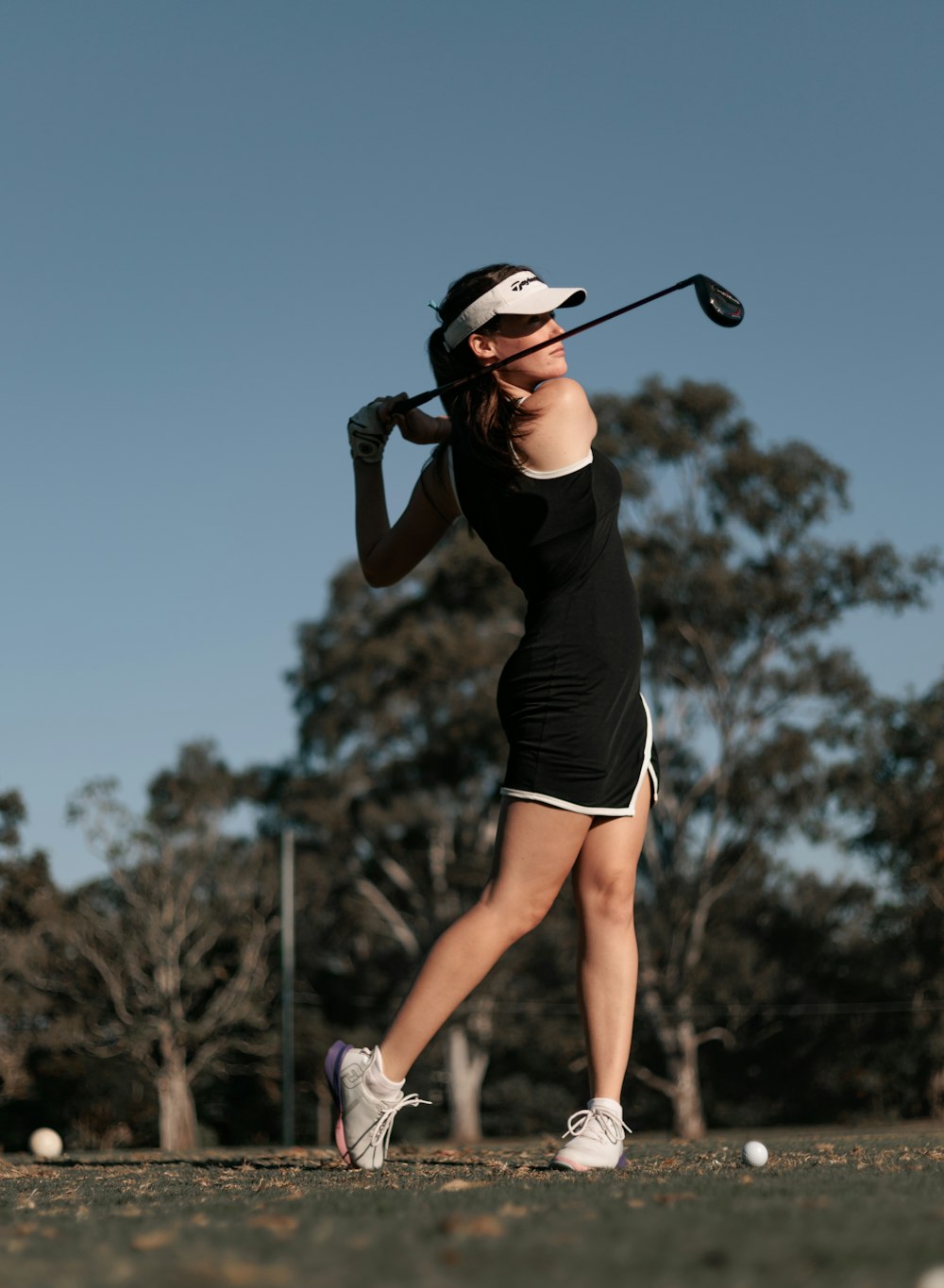 a woman swinging a golf club at a ball