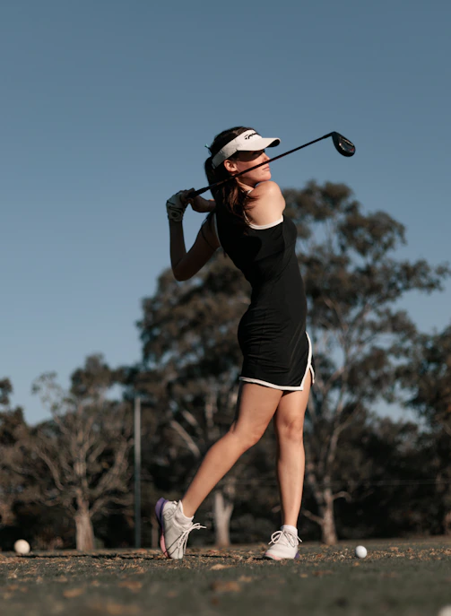 a woman swinging a golf club at a ball