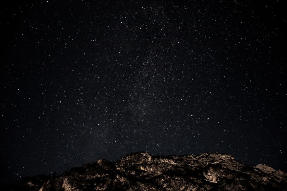 the night sky with stars above a mountain