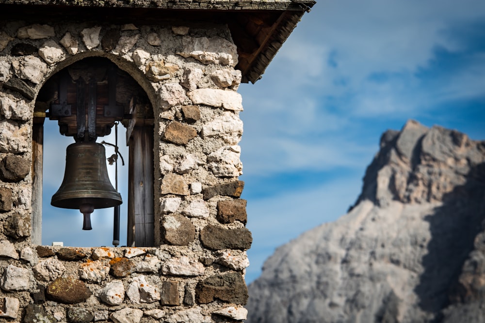 a bell hanging from the side of a stone building