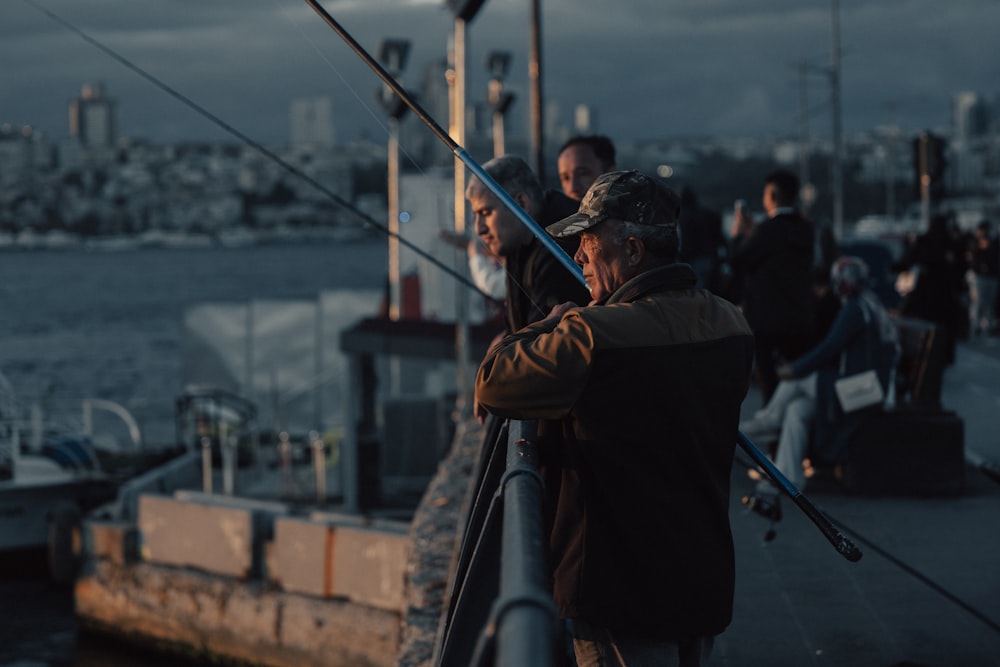 a group of people standing on a pier next to a body of water