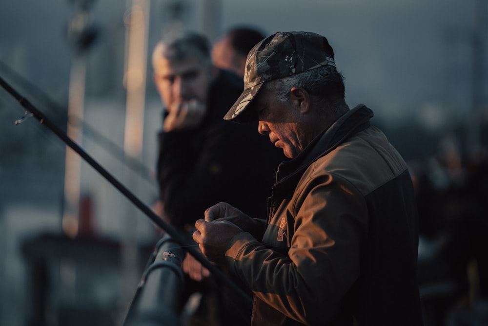 a man standing next to another man holding a fishing pole