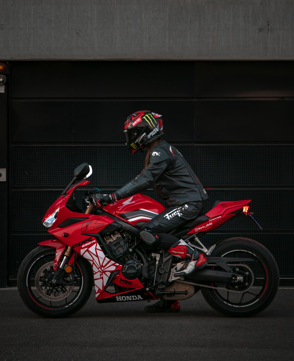 a man riding a red motorcycle next to a garage