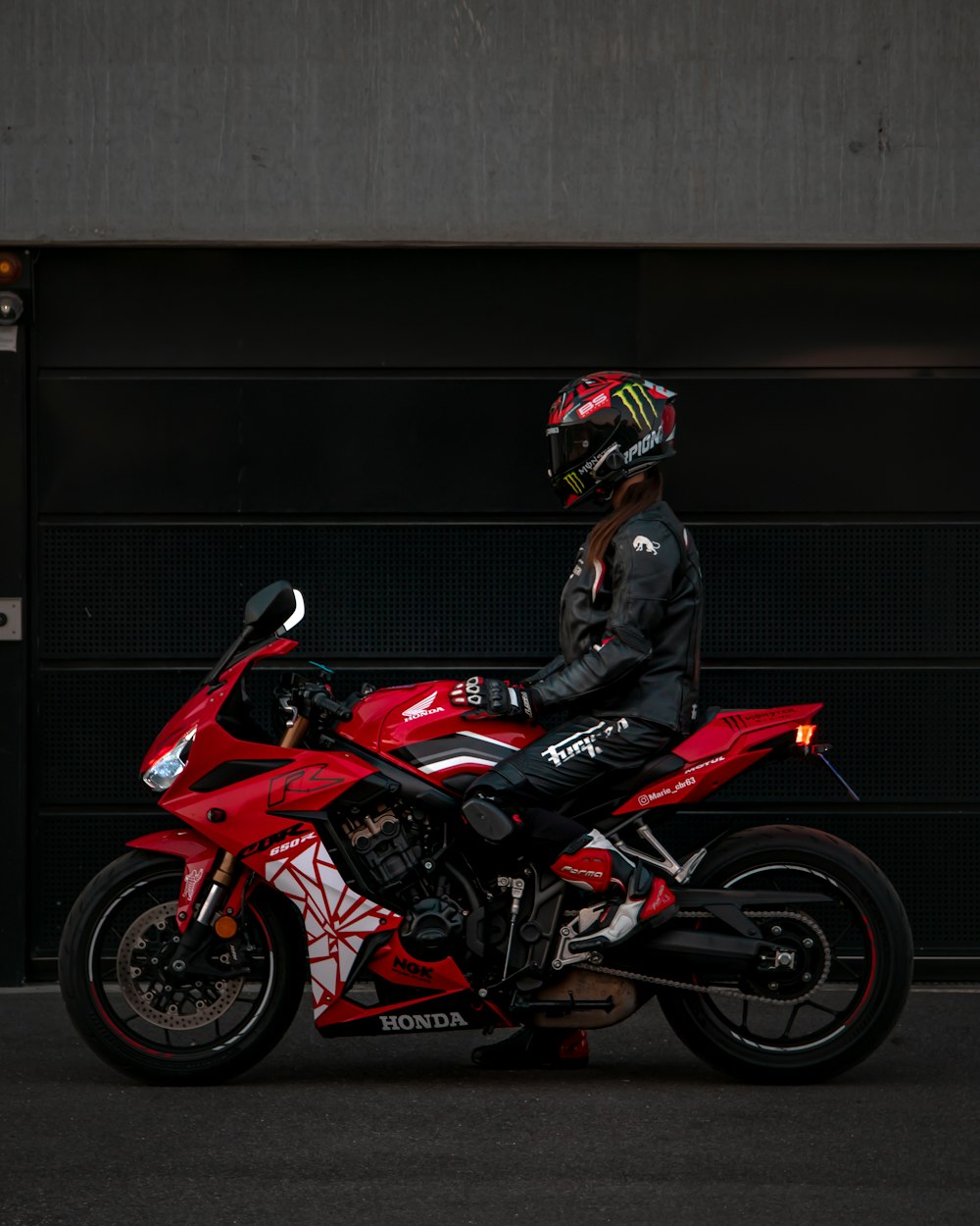 a man riding a red motorcycle next to a garage