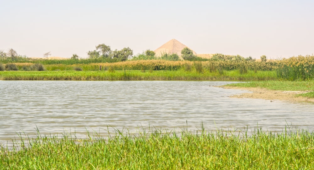 a large body of water surrounded by a lush green field