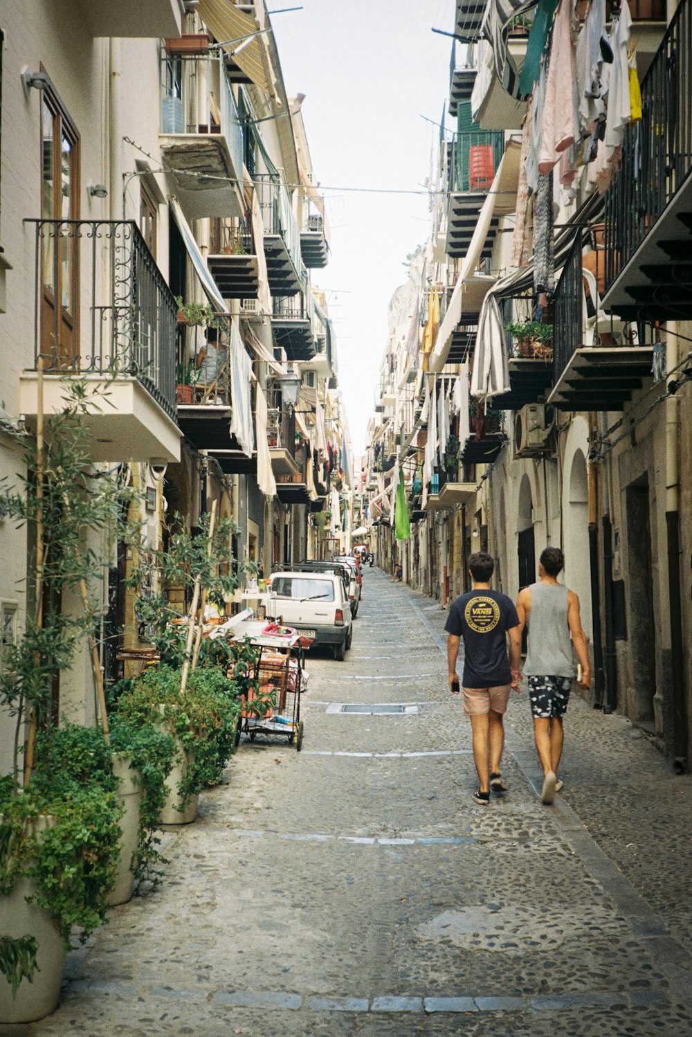 a couple of people walking down a street next to tall buildings