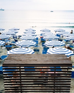 a beach filled with lots of blue and white umbrellas
