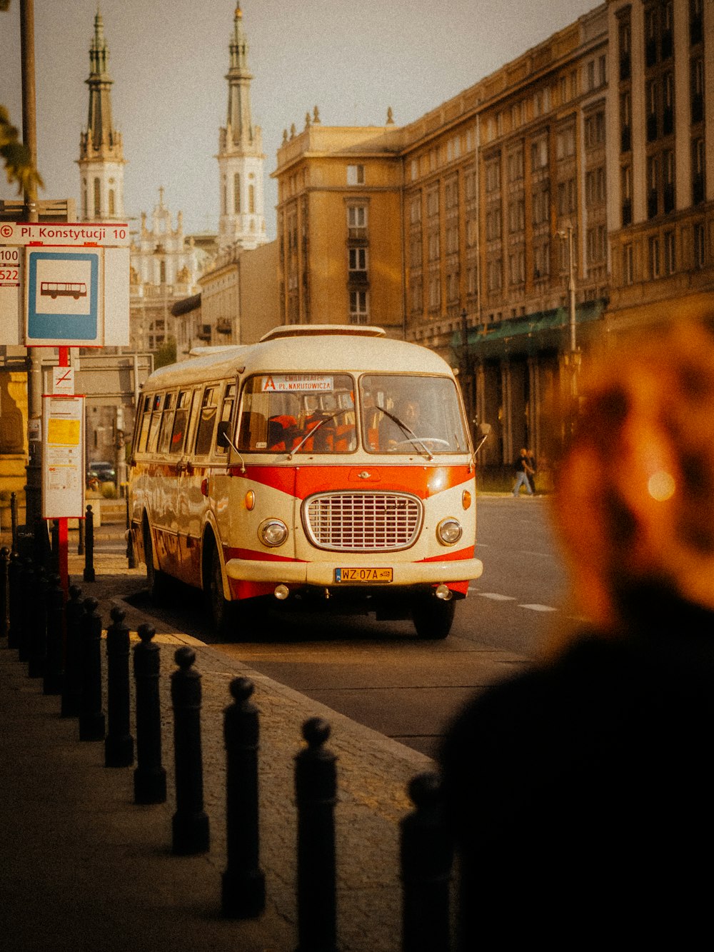 a red and white bus driving down a street next to tall buildings