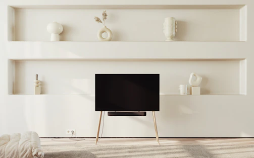 A modern, minimalistic living room featuring a bespoke wooden shelving unit perfectly integrated into the space.