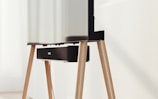 A modern television set up on sleek, angled wooden legs with a soundbar positioned directly beneath it. The design is minimalist and stylish, integrating functionality with aesthetics in a clean, contemporary space.