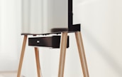 A modern television set up on sleek, angled wooden legs with a soundbar positioned directly beneath it. The design is minimalist and stylish, integrating functionality with aesthetics in a clean, contemporary space.