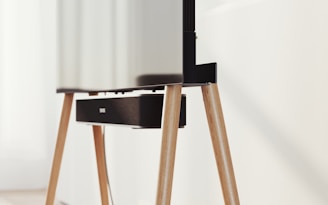 A modern television set up on sleek, angled wooden legs with a soundbar positioned directly beneath it. The design is minimalist and stylish, integrating functionality with aesthetics in a clean, contemporary space.