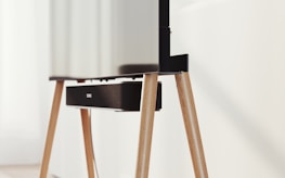 A modern television set up on sleek, angled wooden legs with a soundbar positioned directly beneath it. The design is minimalist and stylish, integrating functionality with aesthetics in a clean, contemporary space.