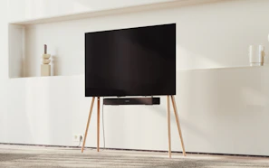 Flat-screen TV mounted on the wall with a wooden dresser beneath it.
