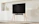 A happy customer standing next to a stylish wooden TV unit in a cozy living room.