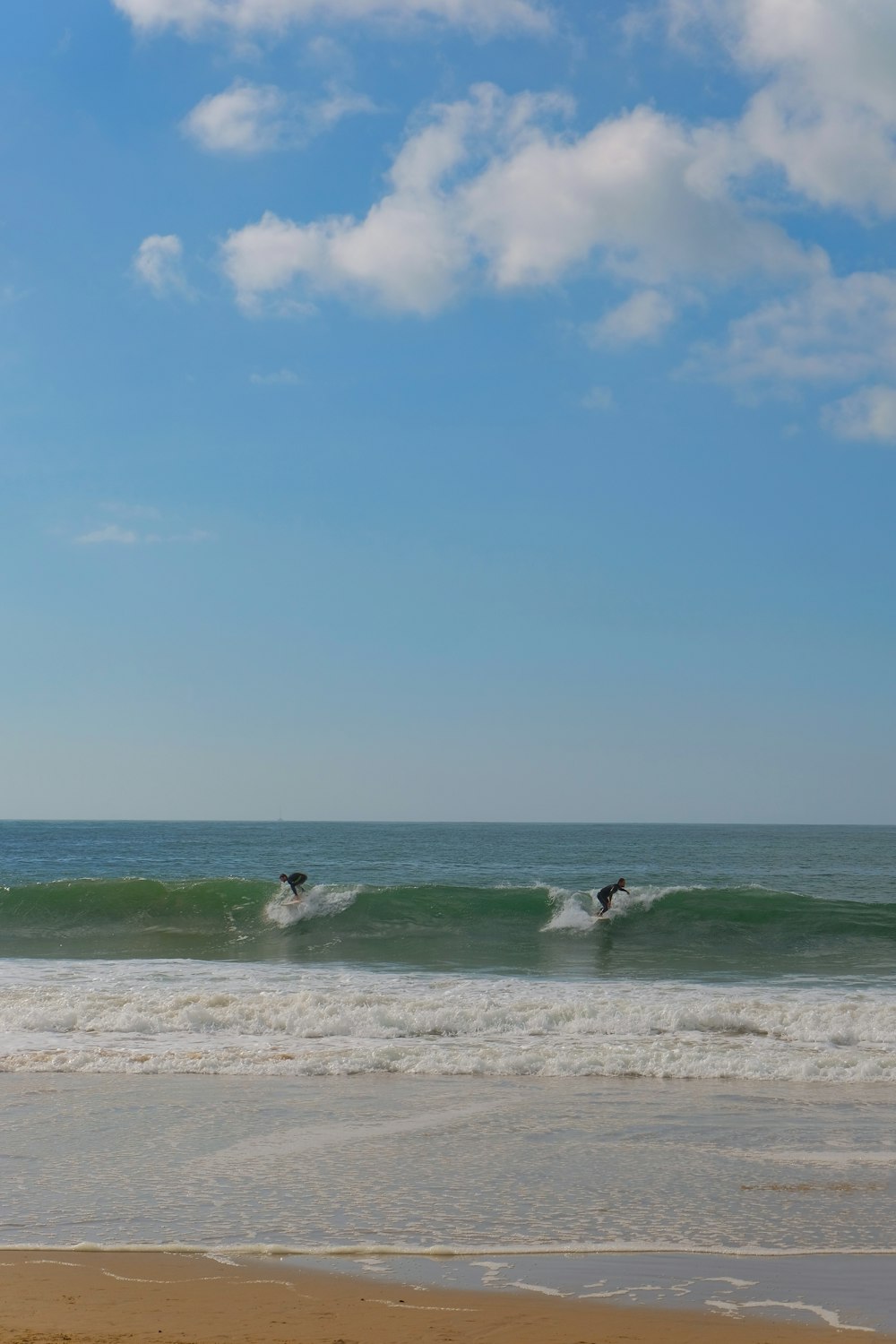 a couple of people riding surfboards on top of a wave