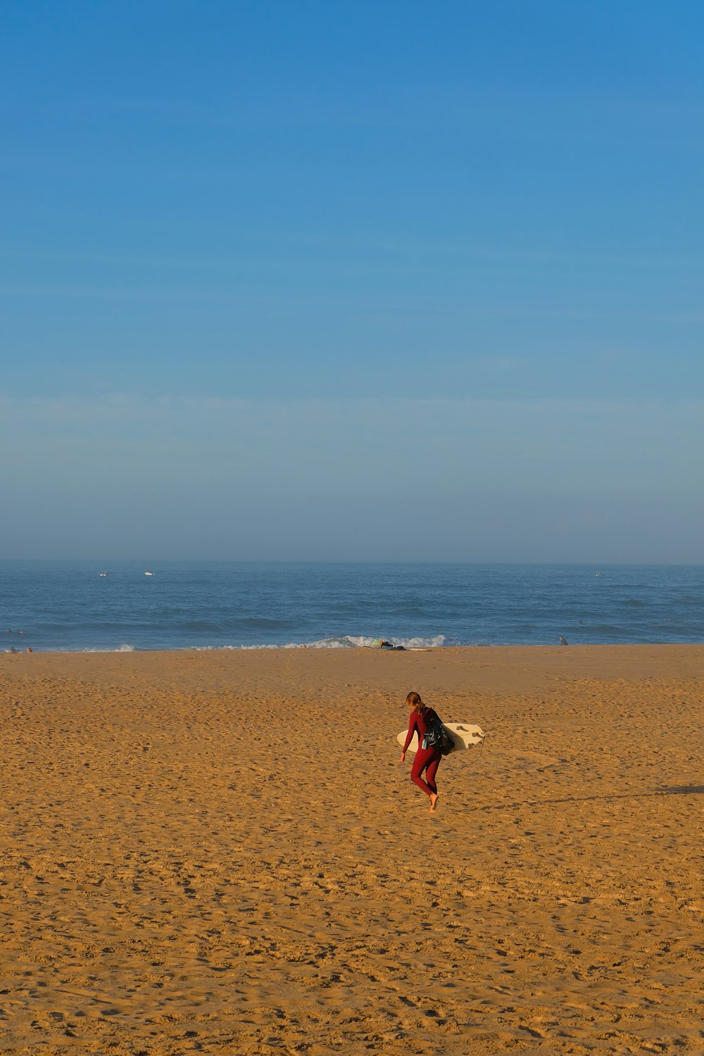 une personne qui court sur une plage avec une planche de surf