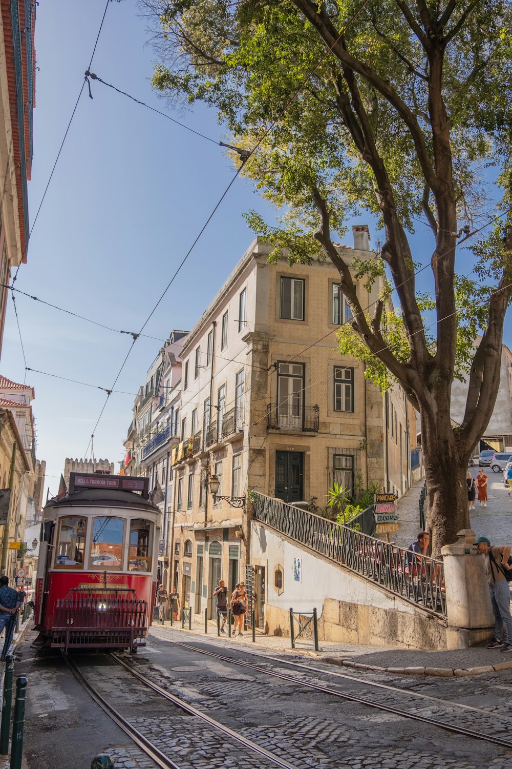 a red trolley car traveling down a street next to a tall building