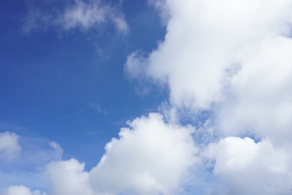 a plane flying through a cloudy blue sky