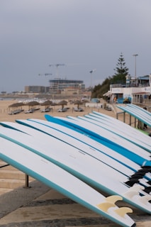 a row of surfboards sitting on top of a sandy beach
